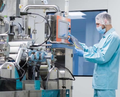 Scientist with hair cover working with complicated machinery