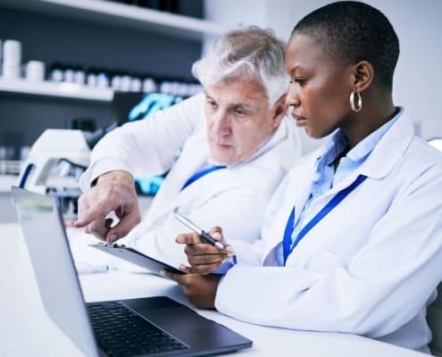 Side view of two doctors looking at a laptop