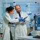 Side view of two medical professionals in lab coats looking at data