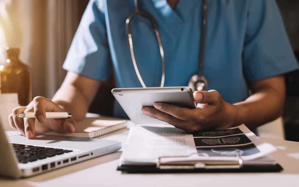 Medical worker using a tablet and laptop