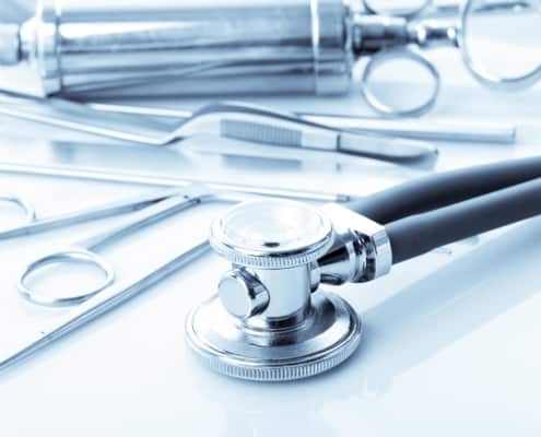 Image focused on a stethoscope with other medical accessories in the background.